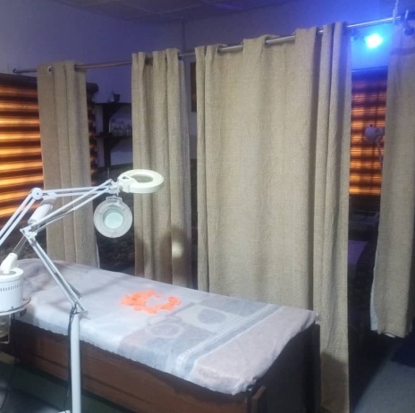 Facial treatment bed with a magnifying lamp and privacy curtains